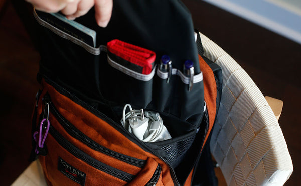 A person accessing a pocket in a Synapse 19 Freudian Slip while it's in the main compartment of the Synapse 19.